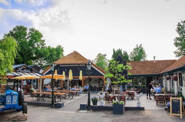 Het gezellige terras van Pannenkoekenboerderij Juffrouw Tok op Landgoed Ruwinkel, waar gasten genieten van een hapje en een drankje.