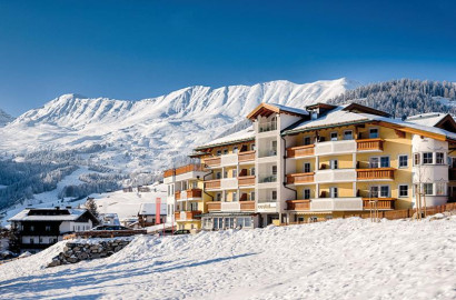 Hotel in de sneeuw met een hoge besneeuwde bergtop achter zich