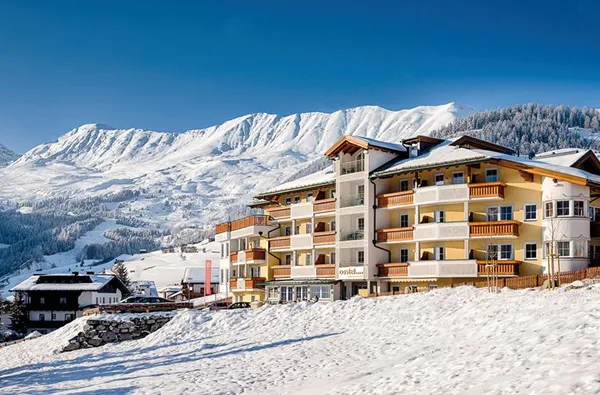 Hotel in de sneeuw met een hoge besneeuwde bergtop achter zich