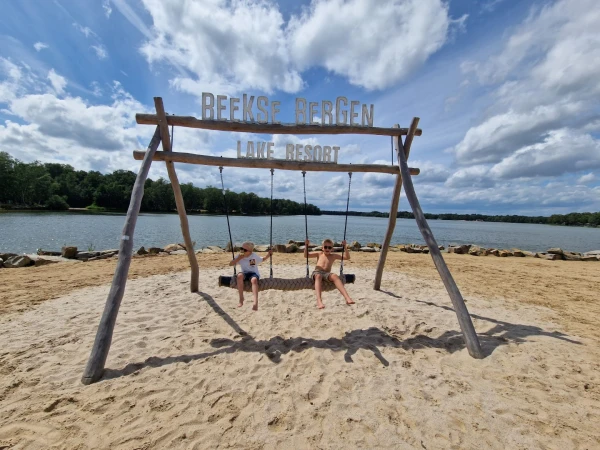 Kinderen schommelen op strand bij Beekse Bergen Lake Resort
