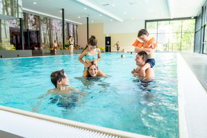 Gezin met kinderen speelt en lacht in het overdekte binnenzwembad van Landal de Vers in Noord-Brabant.