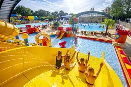 Kinderen roetsjen van de brede gele waterglijbaan in het zwembad