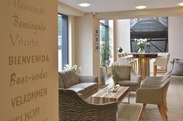 De lobby en zithoek van Parkhotel Oberhausen met welkomstwoorden op de muur