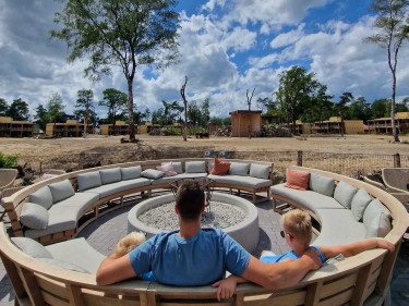 Familie ontspant bij ronde vuurplaats met loungezitjes bij Safari Hotel Beekse Bergen