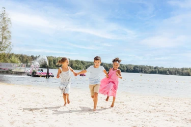 Drie vrolijke kinderen rennen hand in hand over het zandstrand van Beekse Bergen