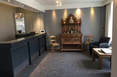 De receptie van Hotel Atlanta waar een modern grijs interieur wordt gecombineerd met een antiek houten dressoir