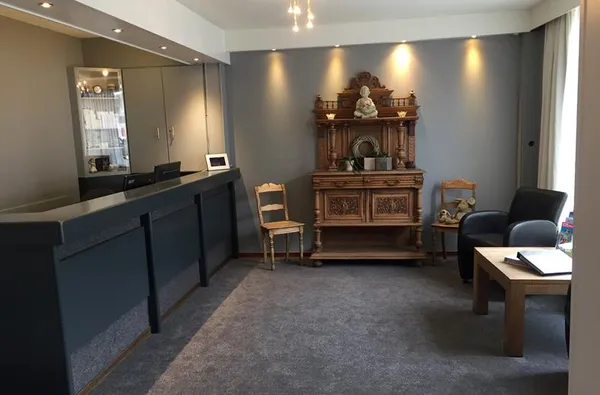 De receptie van Hotel Atlanta waar een modern grijs interieur wordt gecombineerd met een antiek houten dressoir