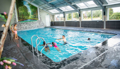 Kinderen zwemmen en spelen in het overdekte binnenzwembad met glazen dak van Residence Lichtenvoorde in de Achterhoek.