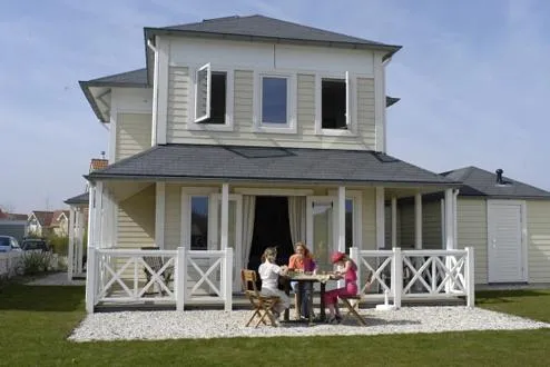 Een gezin dat geniet op het overdekte terras van een luxe, vrijstaande villa op Noordzee Résidence De Banjaard.