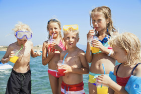 Groep kinderen met snorkel en zwemkleding drinkt limonade op het strand