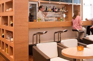 Gasten aan de bar van Ibis Hotel Aken waar een barman drankjes bereidt