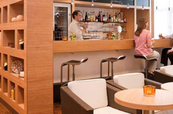 Gasten aan de bar van Ibis Hotel Aken waar een barman drankjes bereidt