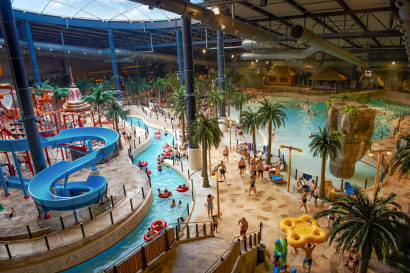 Groot overzicht van het tropische Aquadome waterpark in Lalandia Billund, met de lazy river, het golfslagbad en de vele palmbomen.