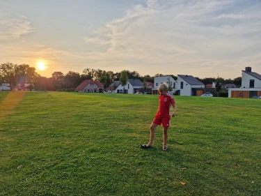 Kind loopt op grasveld bij vakantiepark de Leistert tijdens zonsondergang