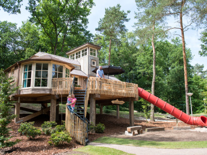 De unieke 4-persoons boomwoning op Landal Miggelenberg met een grote veranda en een eigen rode glijbaan naar beneden.