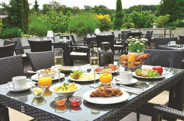 Uitgebreid ontbijt met croissants fruit en jus d'orange geserveerd op het buitenterras van Parkhotel Oberhausen