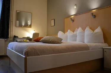 Sfeervolle hotelkamer in Hotel Atlanta met een opgemaakt bed met sierkussens en een verlicht bureau op de achtergrond