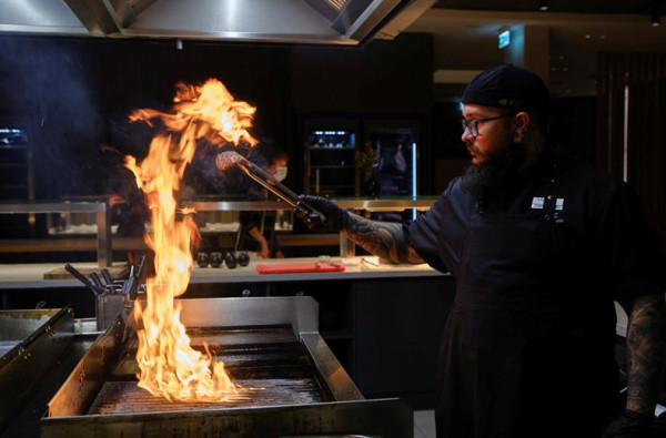 Chef bereidt een gerecht op de grill in de open keuken van ATLANTIC Hotel Münster