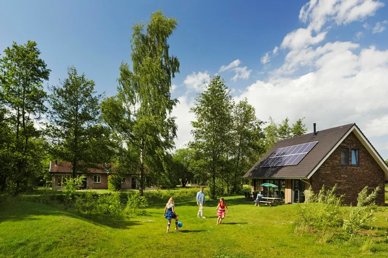 Overzicht van het ruim opgezette vakantiepark Landal Aelderholt met vrijstaande bungalows, omgeven door grote groene grasvelden en de Drentse bossen.
