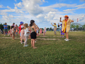Kinderen dansen buiten met het animatieteam op een groot grasveld