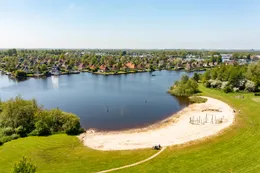 Overzicht van het kindvriendelijke zandstrand van Vakantiepark It Wiid, ideaal om te spelen en te zwemmen in het ondiepe water.