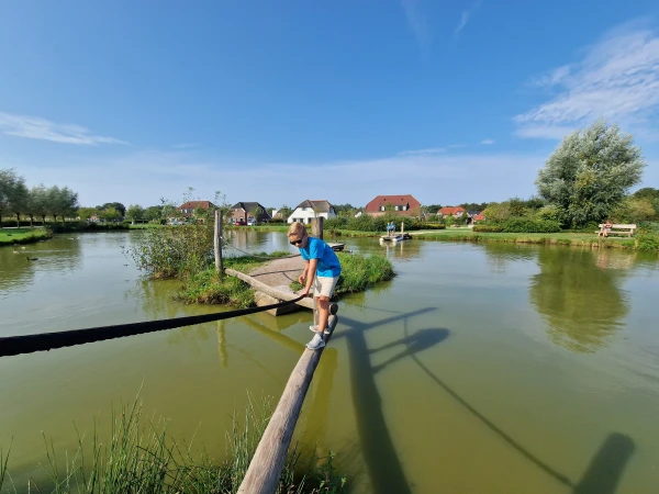 Kind loopt over evenwichtsbalk boven vijver van Vakantiepark de Leistert