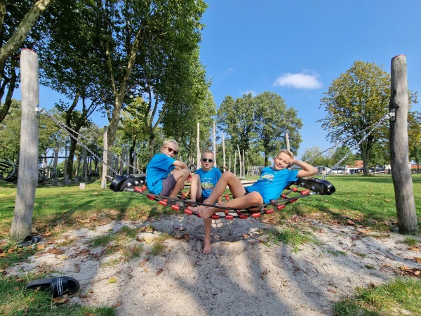 Kinderen ontspannen in hangnet bij speeltuin van vakantiepark De Leistert