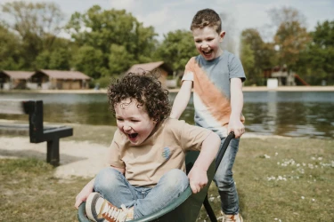 Kinderen spelen met kruiwagen bij zwemvijver en strand Vakantiepark Dierenbos