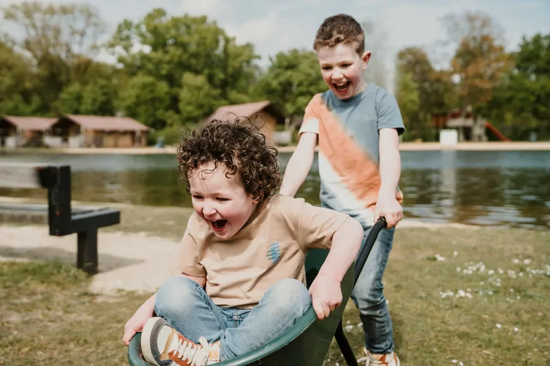 Kinderen spelen met kruiwagen bij zwemvijver en strand Vakantiepark Dierenbos