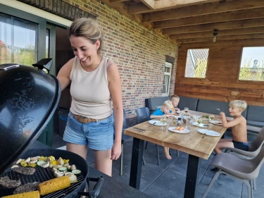 Gezin barbecuet op veranda van vakantiehuis bij Recreatiepark de Leistert