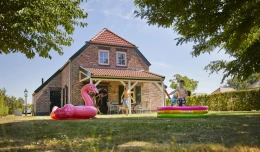 Drie kinderen zijn in de tuin van hun vakantie huis aan het spelen met water.