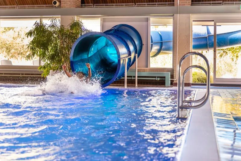 De grote, blauwe tunnelglijbaan in het overdekte zwembad van Vakantiepark Aquadelta zorgt voor een spetterend einde in het water.